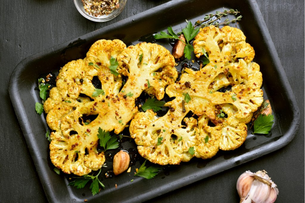 Baked cauliflower with some herbs on baking pan. Getting nutrients from vegetables means knowing which vegetables retains their nutritional content with heat.