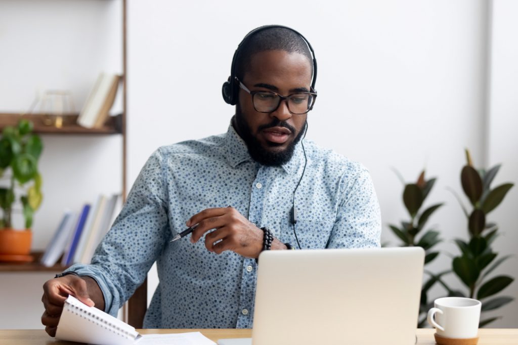 Man sitting at table wearing headphones listening to an audio file.