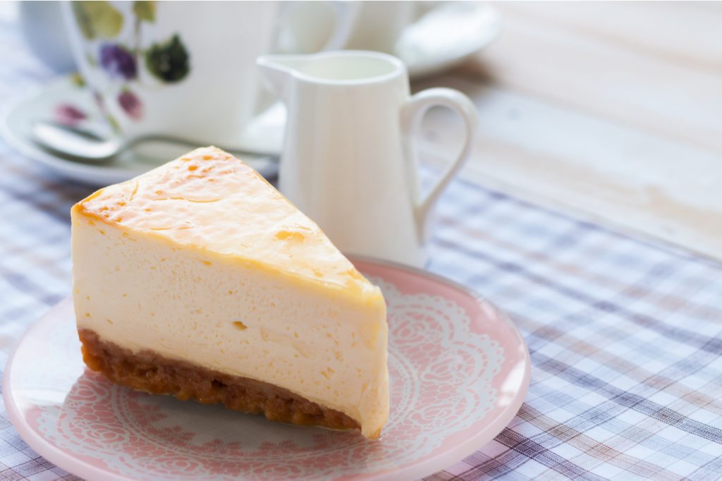 Slice of new york style cheesecake with a cup of tea.