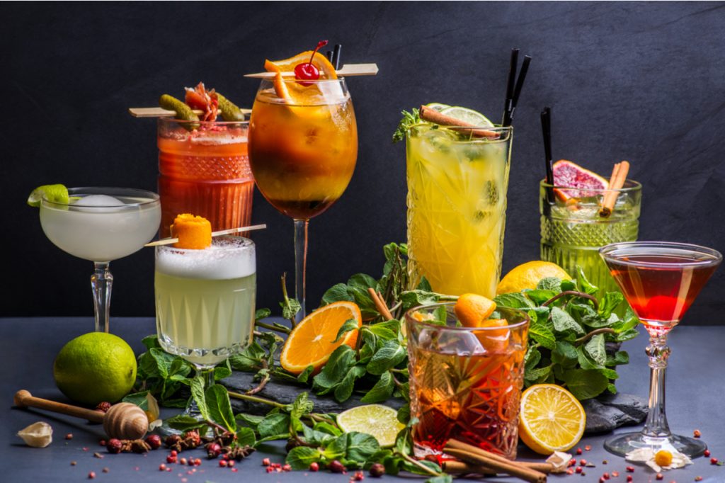A variety of healthy cocktails surrounded by slices of lemon, oranges and mint leaves.