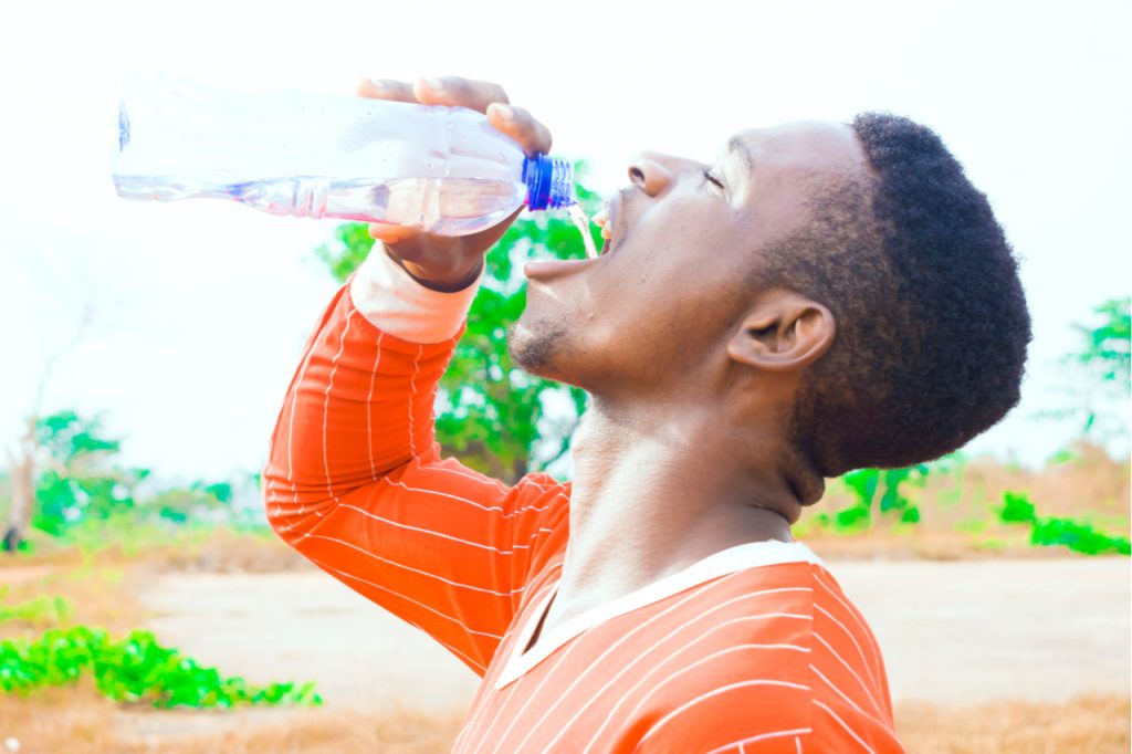An African American man drinking water after working out. 