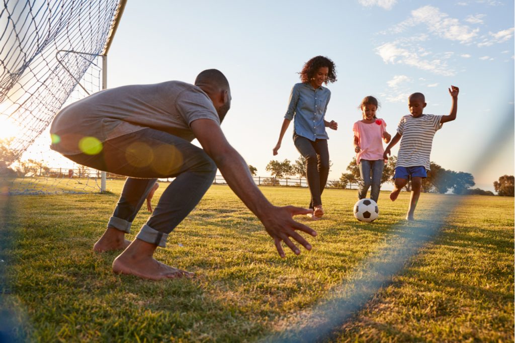 A boy kicks a football during a game with his family as part of the 9 tips for a safe, fun and healthier 4th of July celebration.