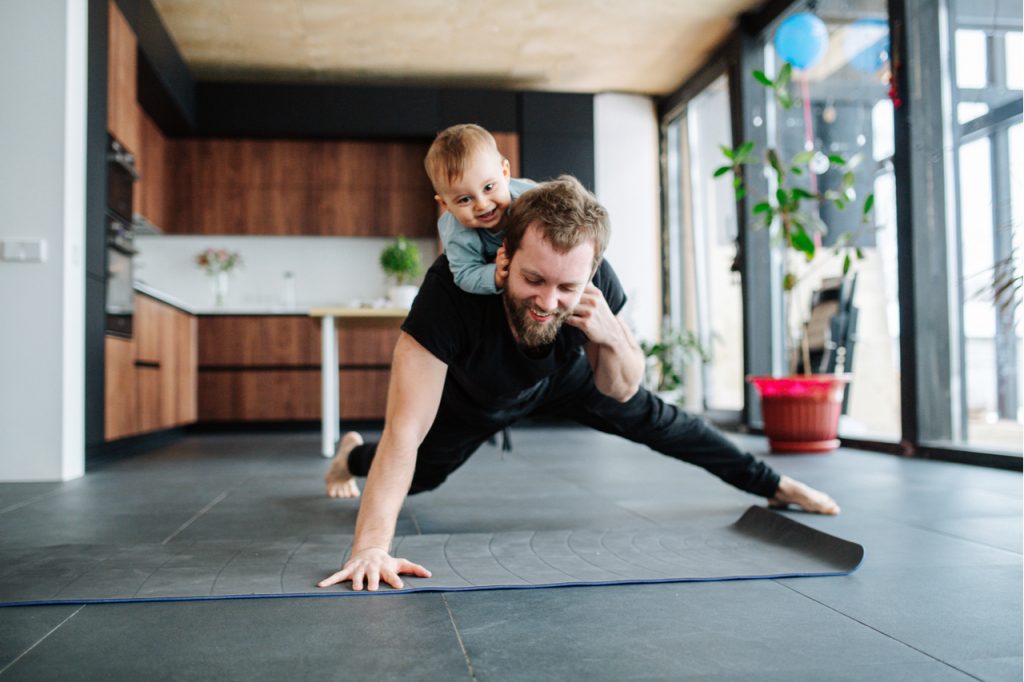 A father doing some push-ups while giving his son a piggy back ride. What an active way to spend father's day in 2020.