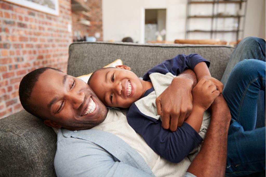 Father and son happily cuddling on sofa.