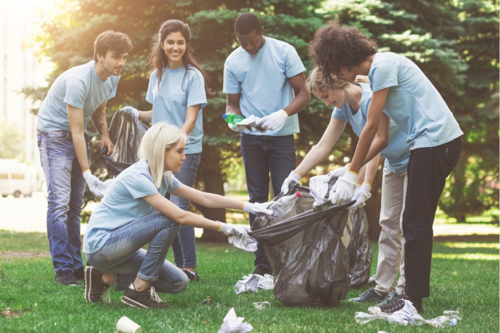 Young millennial volunteers picking garbage in park.