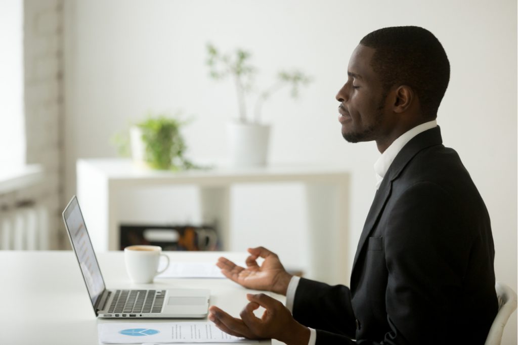 Businessman in suit meditating in office.