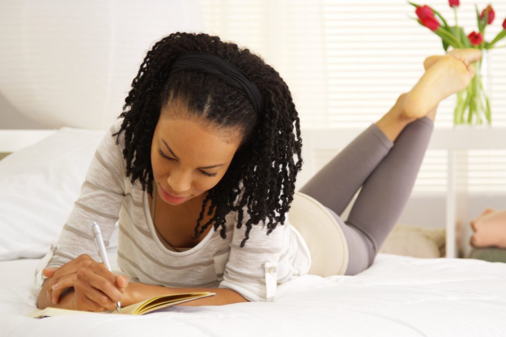 Woman in yoga wear writing in her journal.