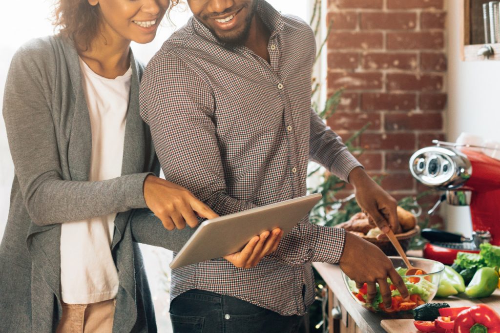 Couple using digital tablet at kitchen.
