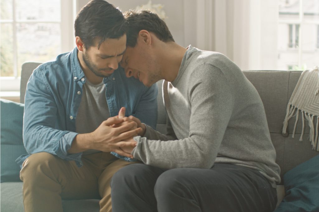 Depressed looking LGBTQ individual with his friend comforting him. Depression comes to a lot of people in the LGBTQ community.