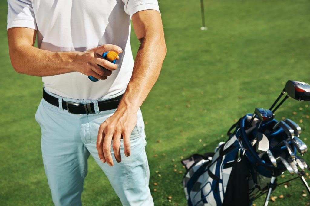 Golf sport man with sunblock lotion spray for spf protection.