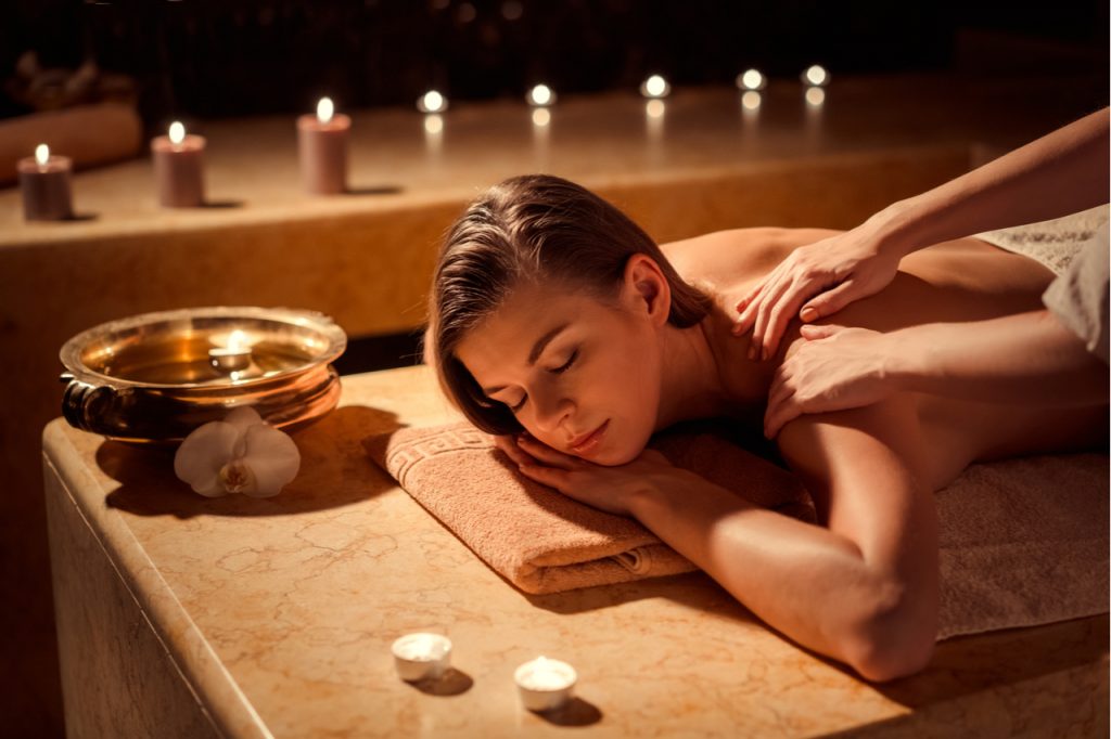 A woman having a back massage with candles for her to relax quickly.