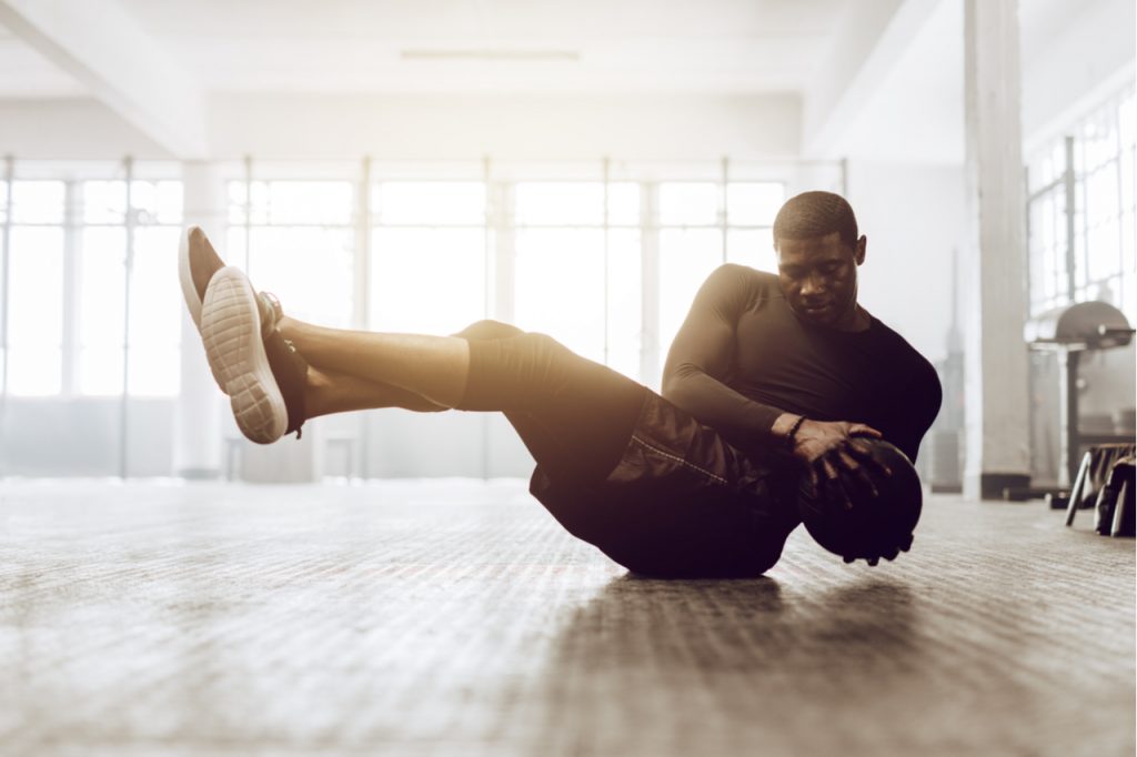 An Afro American man doing medicine ball workout.