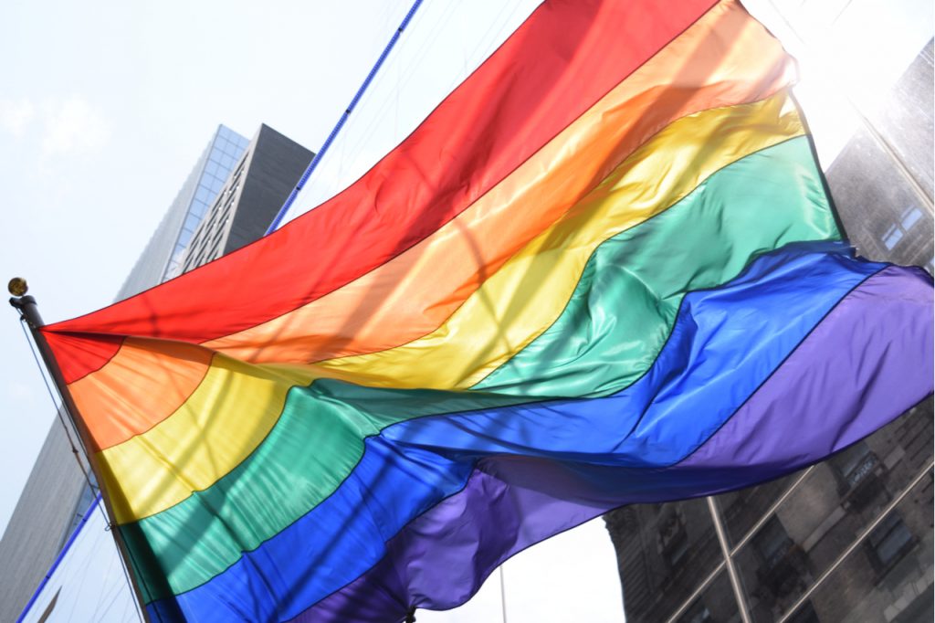 Rainbow flag on new building facing an old building for pride month.