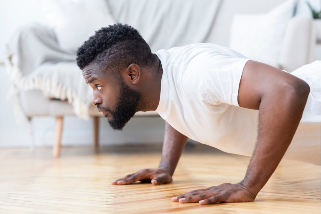 Man exercising at home doing push ups.