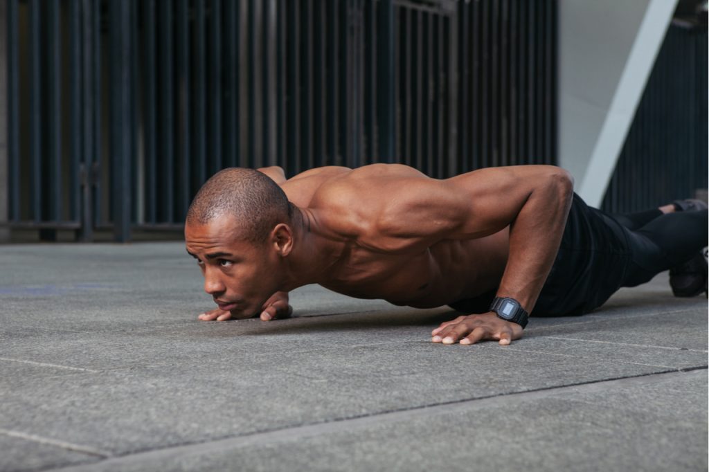 A fit Afro American man doing push-ups.