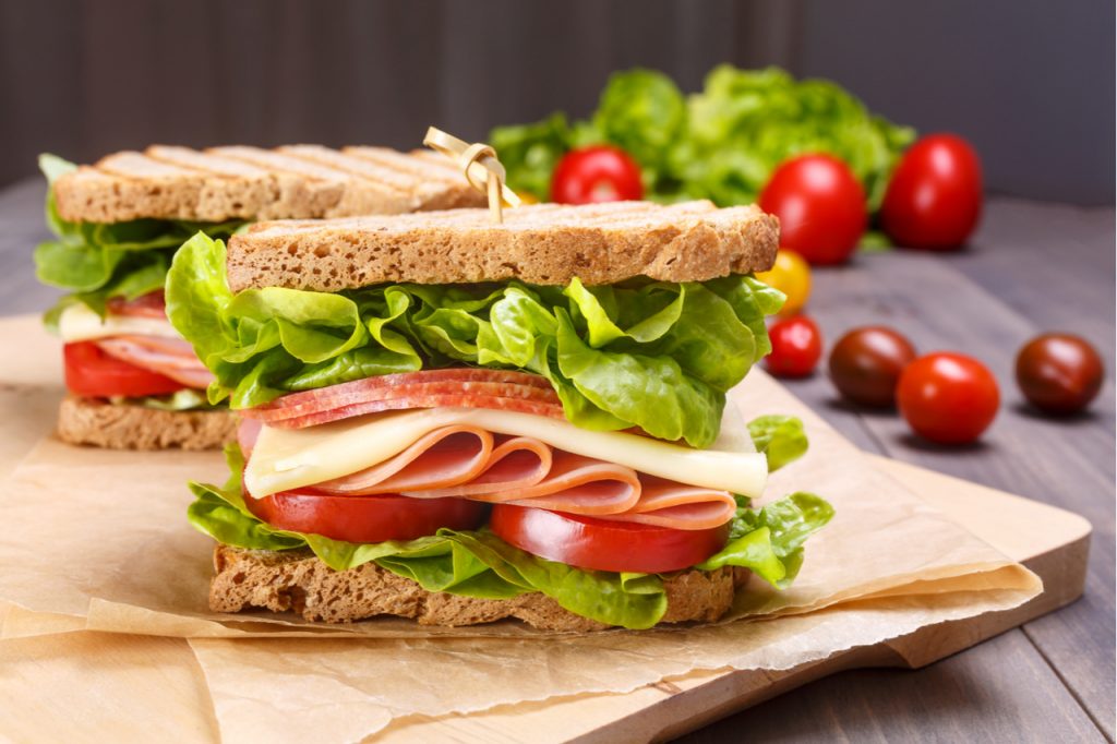 Sandwich with salami, cheese, tomatoes and greens.