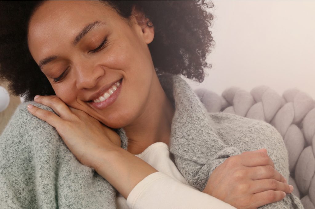 A woman looking like she's hugging herself showing that she loves herself and is expressing self-acceptance.