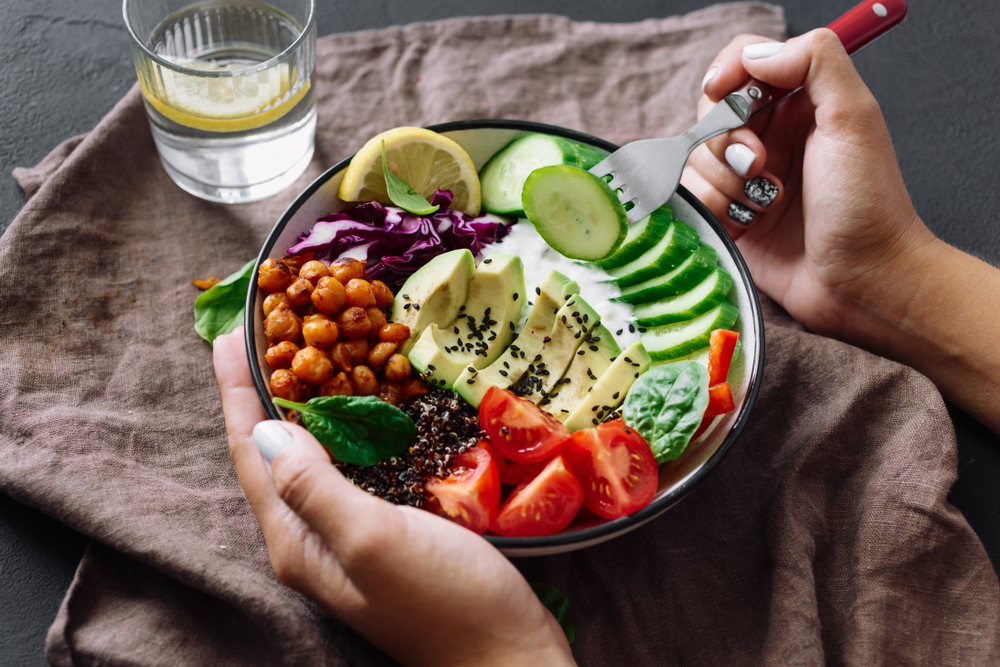 Woman is eating healthy lunch on dark background.