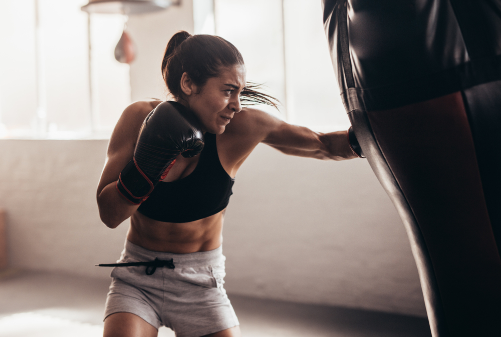 Fitness sporty woman working out on a punching bag.