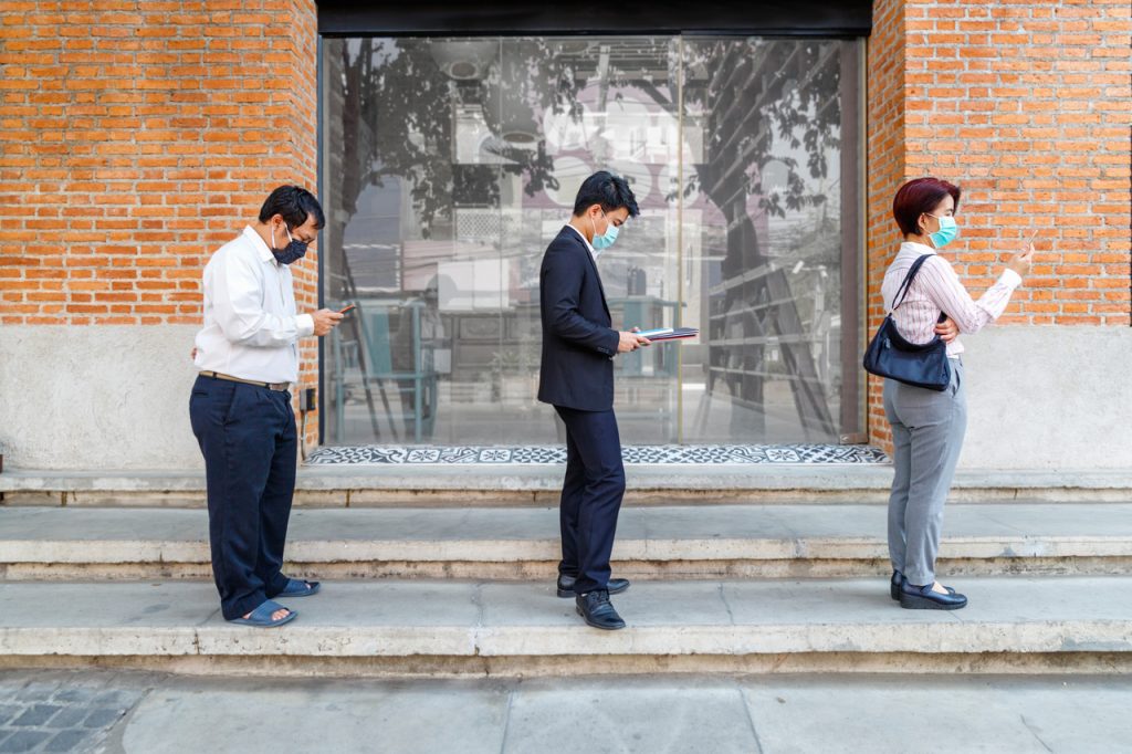 People waiting in line wearing protective masks and maintaining social distance.