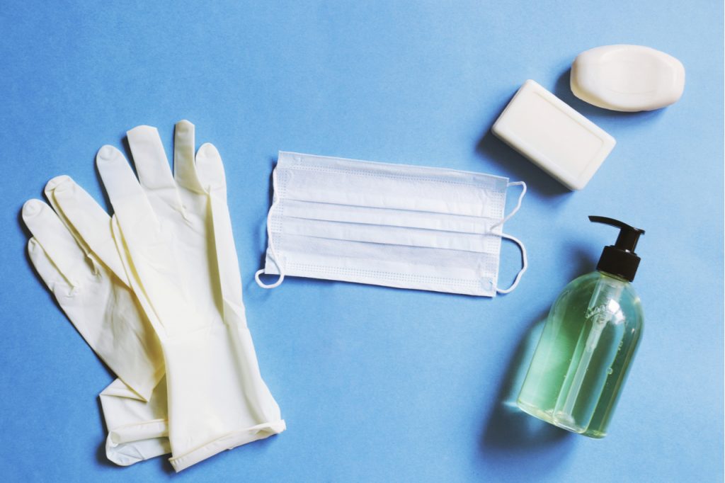 Latex gloves, medical mask, soap bar, sanitizer gel for home self-care ideas.
