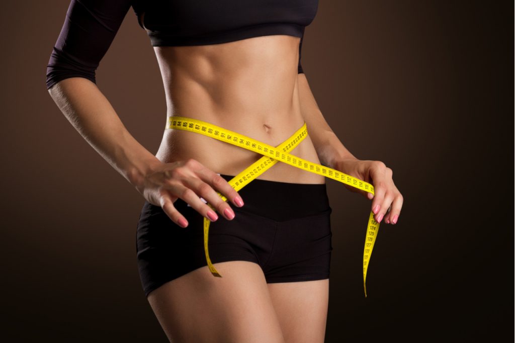 A woman measuring her waistline using a measuring tape. What is the best diet to loss weight?