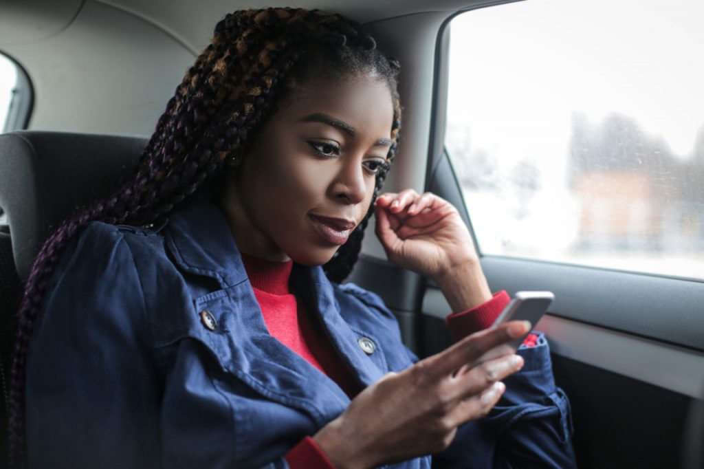 A woman reading news on her phone while in the car.