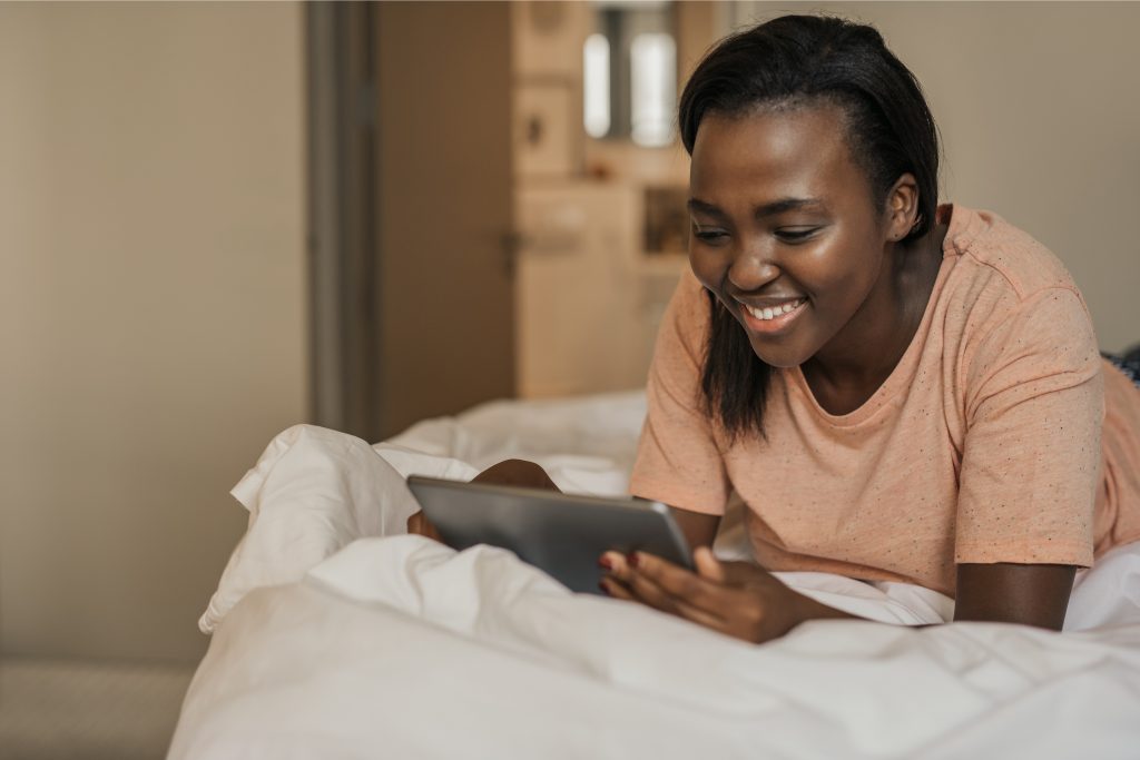 A young African American Woman with a big smile while watching videos on YouTube.
