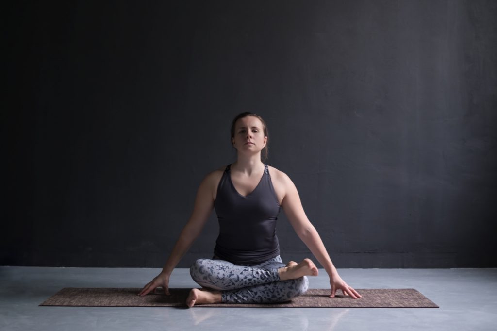 Woman working out, doing yoga exercise on floor agnistambhasana.