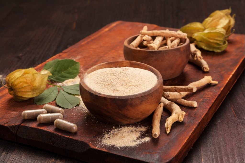 Roots and powder of Ashwagandha also known as Indian ginseng an adaptogenic herb on wooden background.