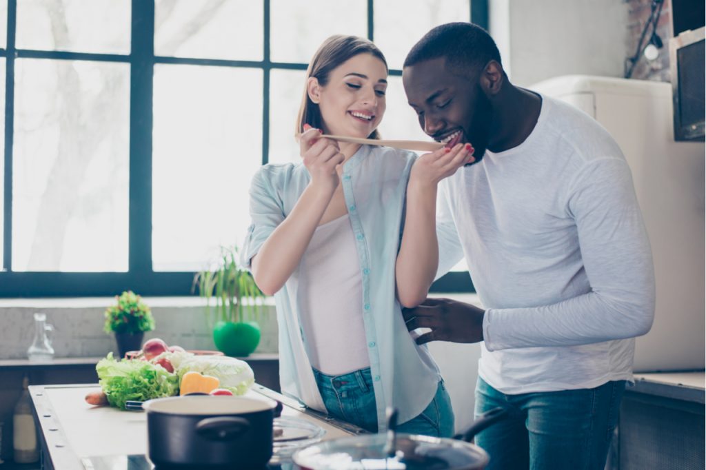 A multi racial couple cooking at the kitchen.