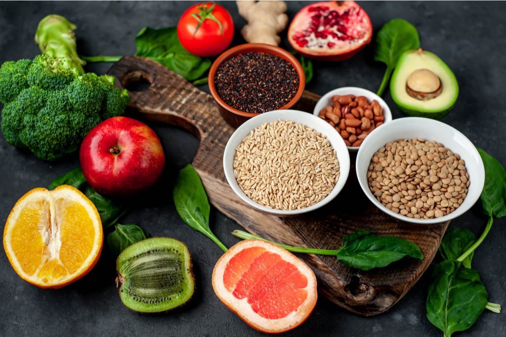 Complex carbohydrates like whole grains in bowls, nuts, oranges, kiwi, apple, avocado, pomegranate, broccoli and tomato.