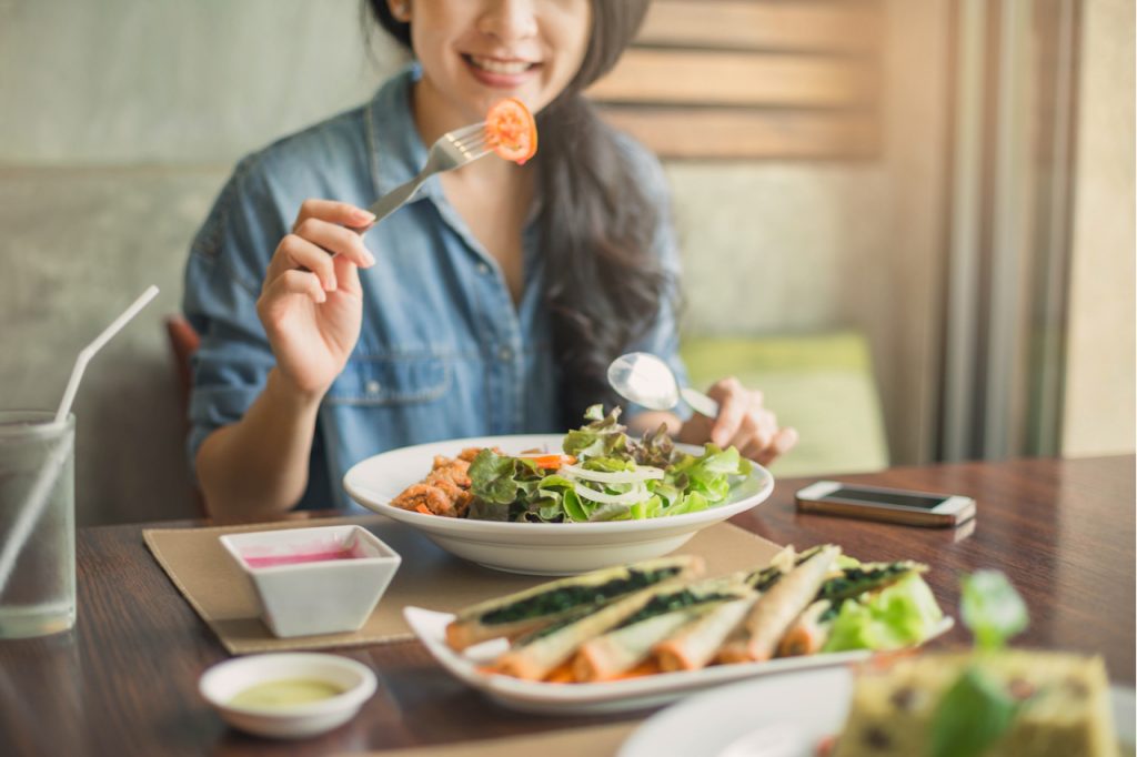 A woman eating vegetables on the table showing how to eat more vegetables.