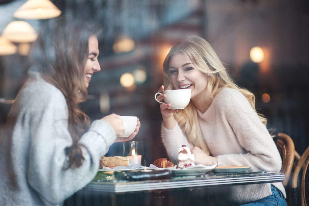 Two girl friends drinking coffee in the cafe.
