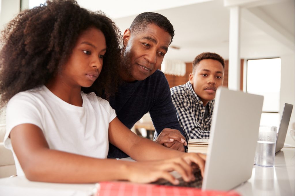Father spending time with teenager kids while they engage in Social media.