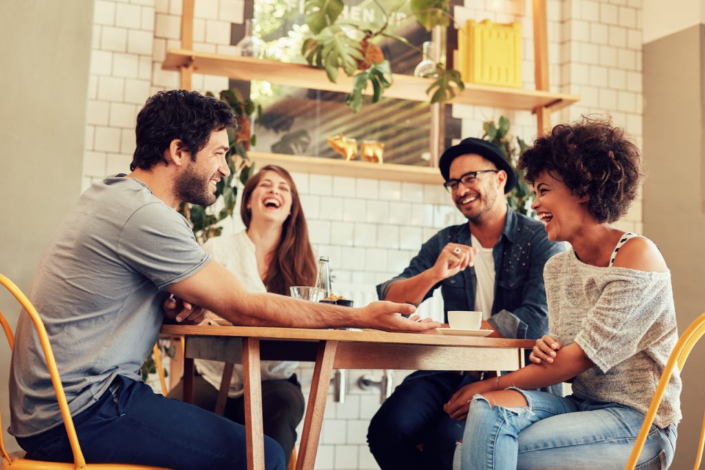 A group of friends having a good laugh while having a coffee. What is social wellness and how it can affect you?