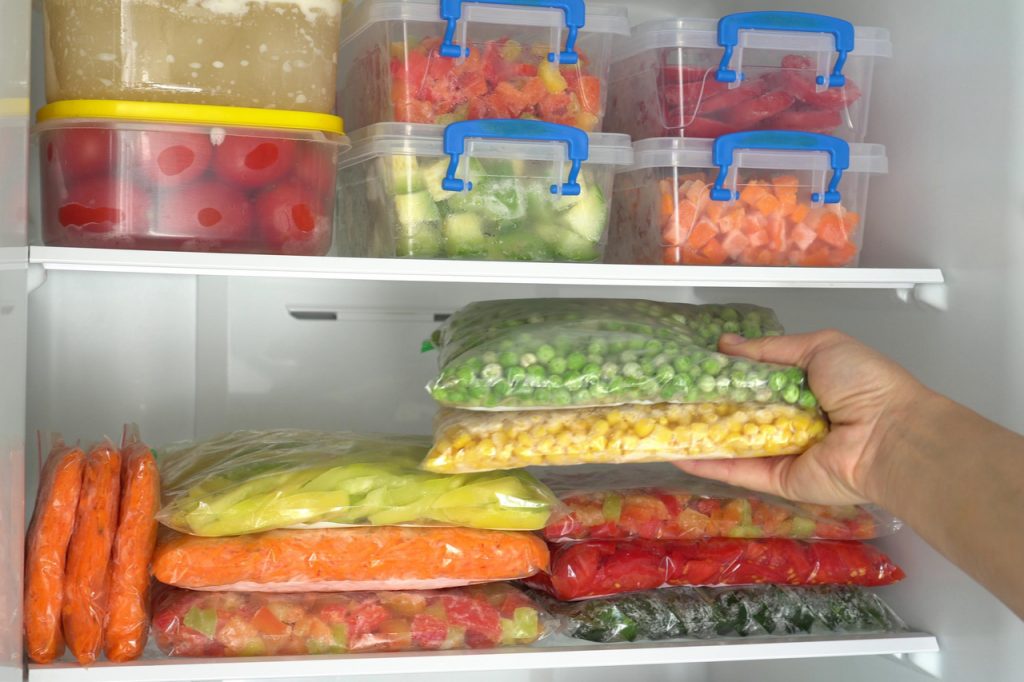 Frozen vegetables stack up in a freezer. 