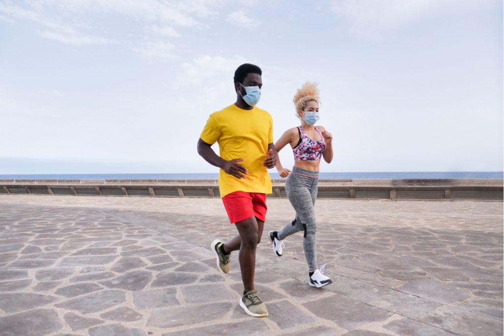 Young active couple do sports together and wearing protective face mask.
