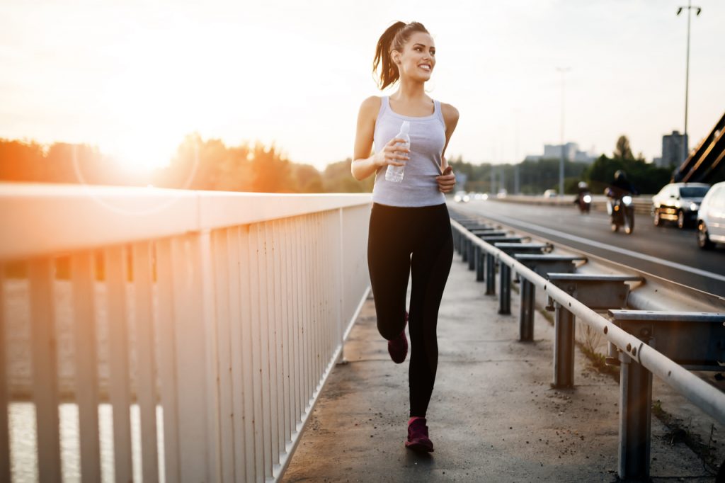 A happy looking woman jogging in the morning.