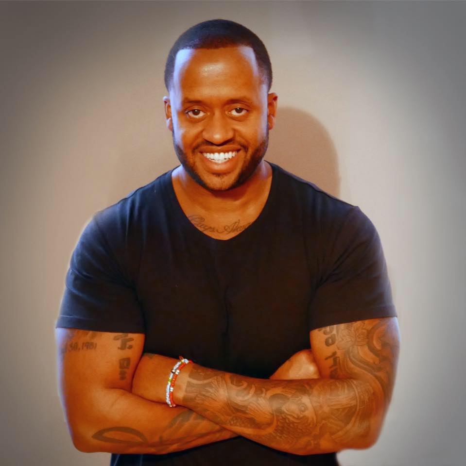 Kenny Hamilton wearing a black shirt with dirty white background.