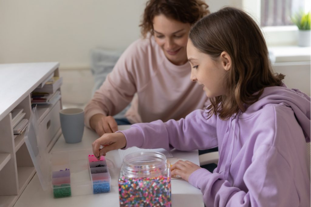 Mother and teen daughter bonding, talking and doing a mosaic at home.