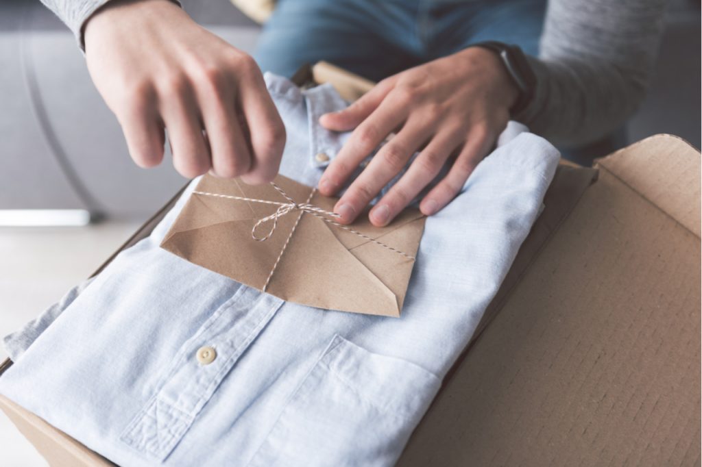 A man untying a letter from a gift box with a shirt inside.