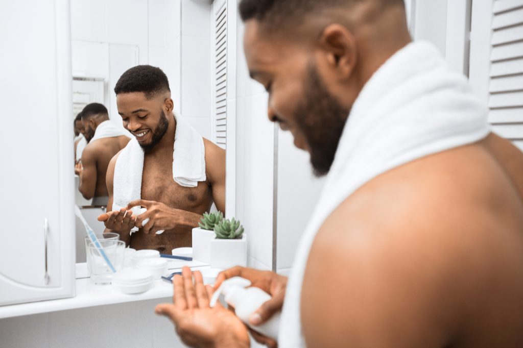 Man doing self care routine squeezing cream on his hand.