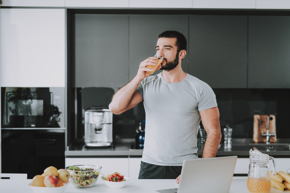 Athletic Man Drinks Fresh Juice On The Kitchen.