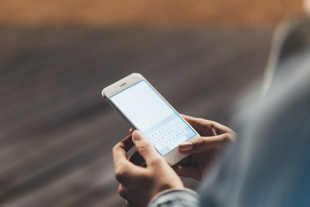 Girl pointing finger on screen smartphone on background wooden floor in night atmospheric city,