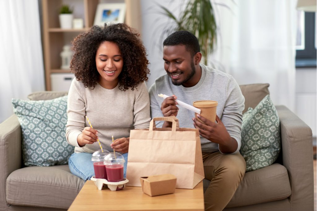 Couple with takeaway food and drinks at home.