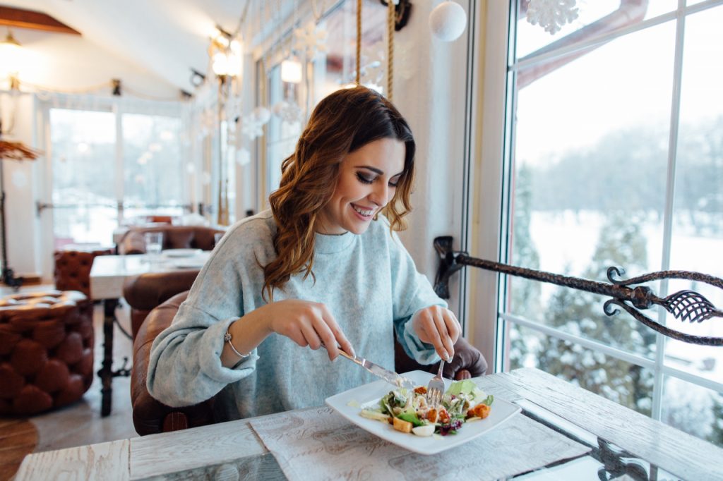 A woman eating healthy food in a restaurant.