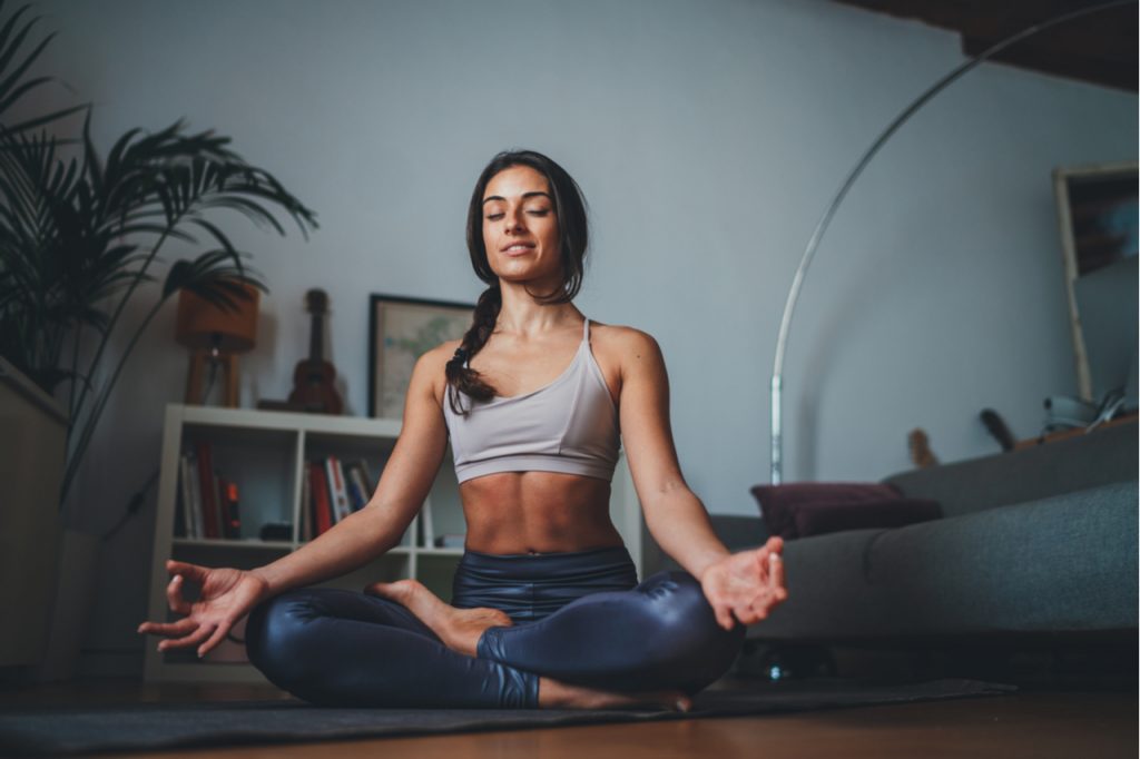 Fit woman practicing mindfulness meditation at home.