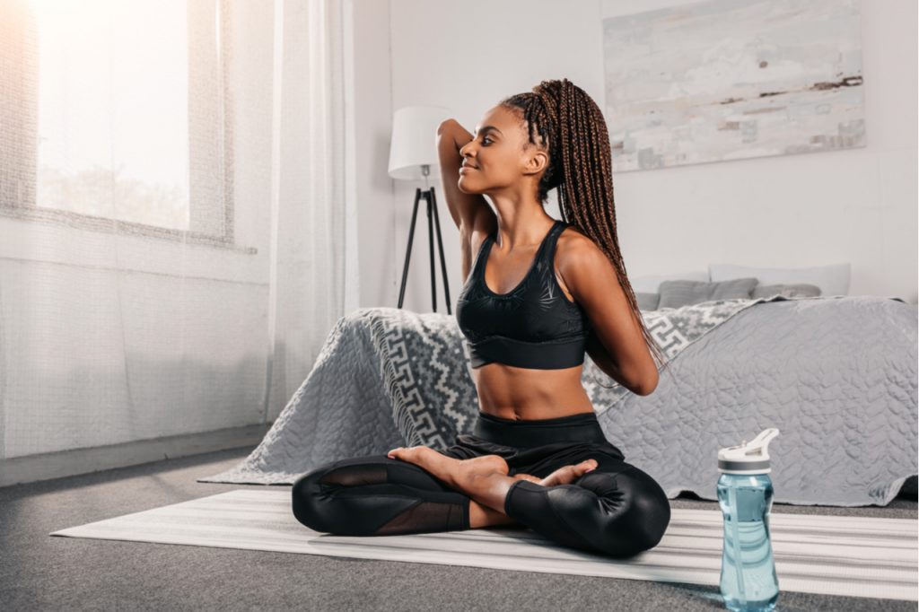 Beautiful woman doing yoga in her bedroom.