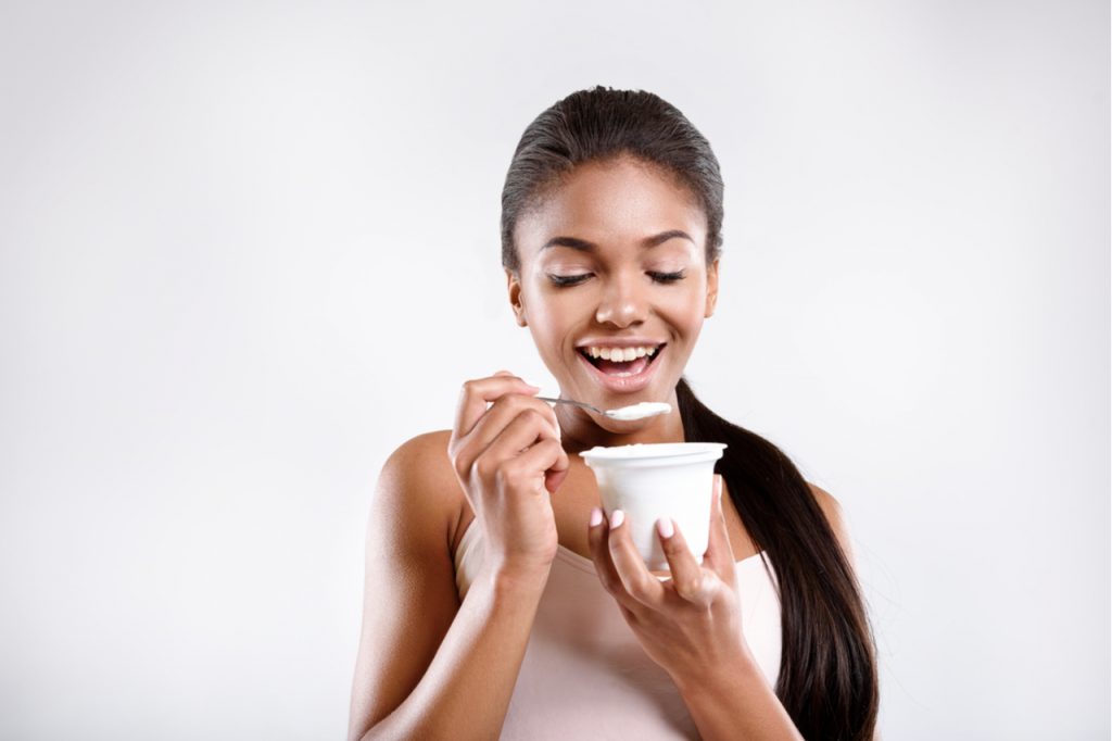 Happy woman is eating yogurt.